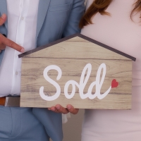 Sold sign being held by happy clients
