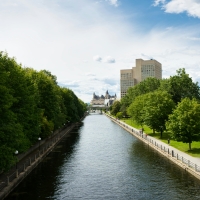 Rideau Canal flowing into the distance with a boardwalk on either side and parliament in the background