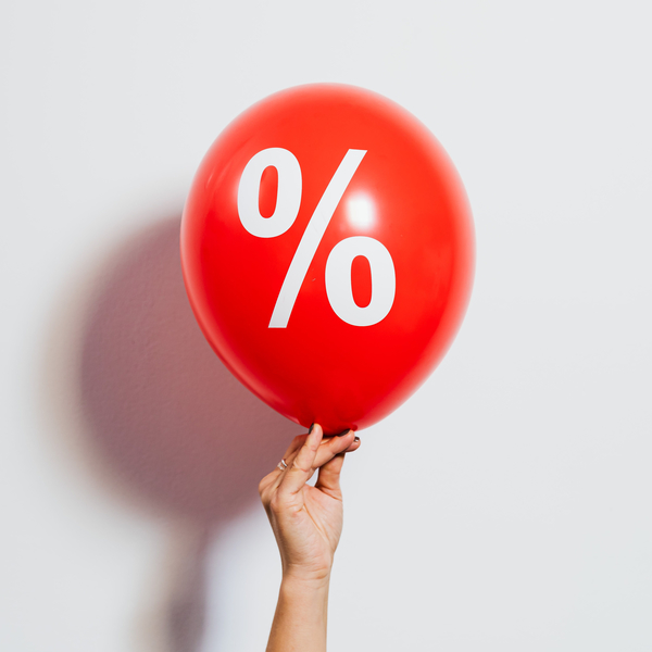 Hand holding a red balloon with a white percentage sign